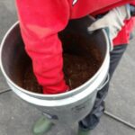 hand in a bucket of soil