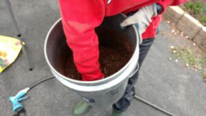 hand in a bucket of soil
