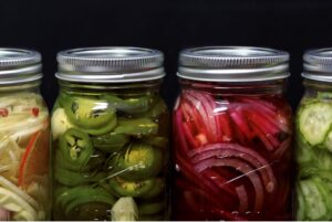 Canned pickled vegetables. The jars are filled with jalapeños, red onions and cucumbers.