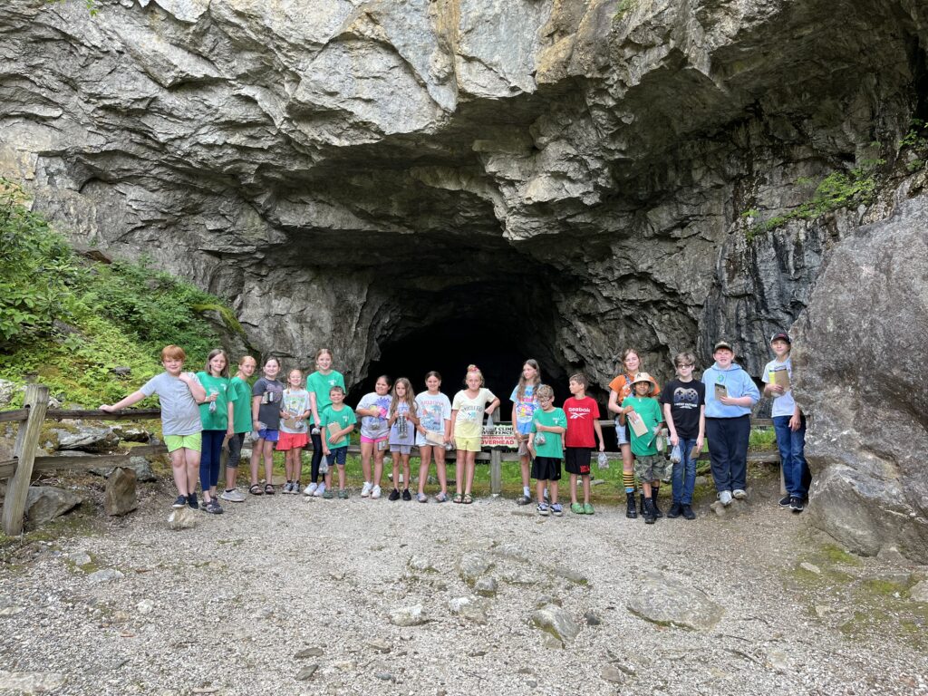 Children posing in front of a cave entrance.